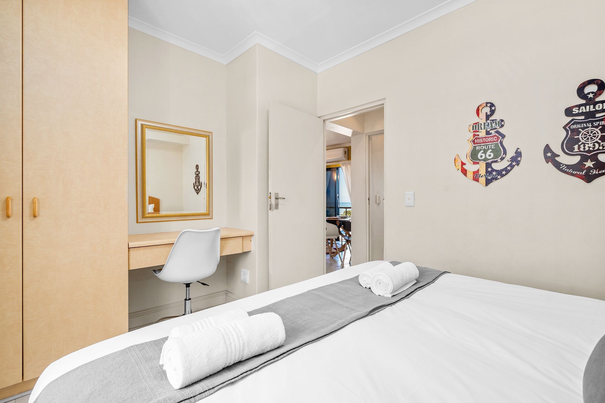 Een hotelkamer met een bed, een bureau, een stoel en een kledingkast. Er hangen twee decoraties aan de muur.