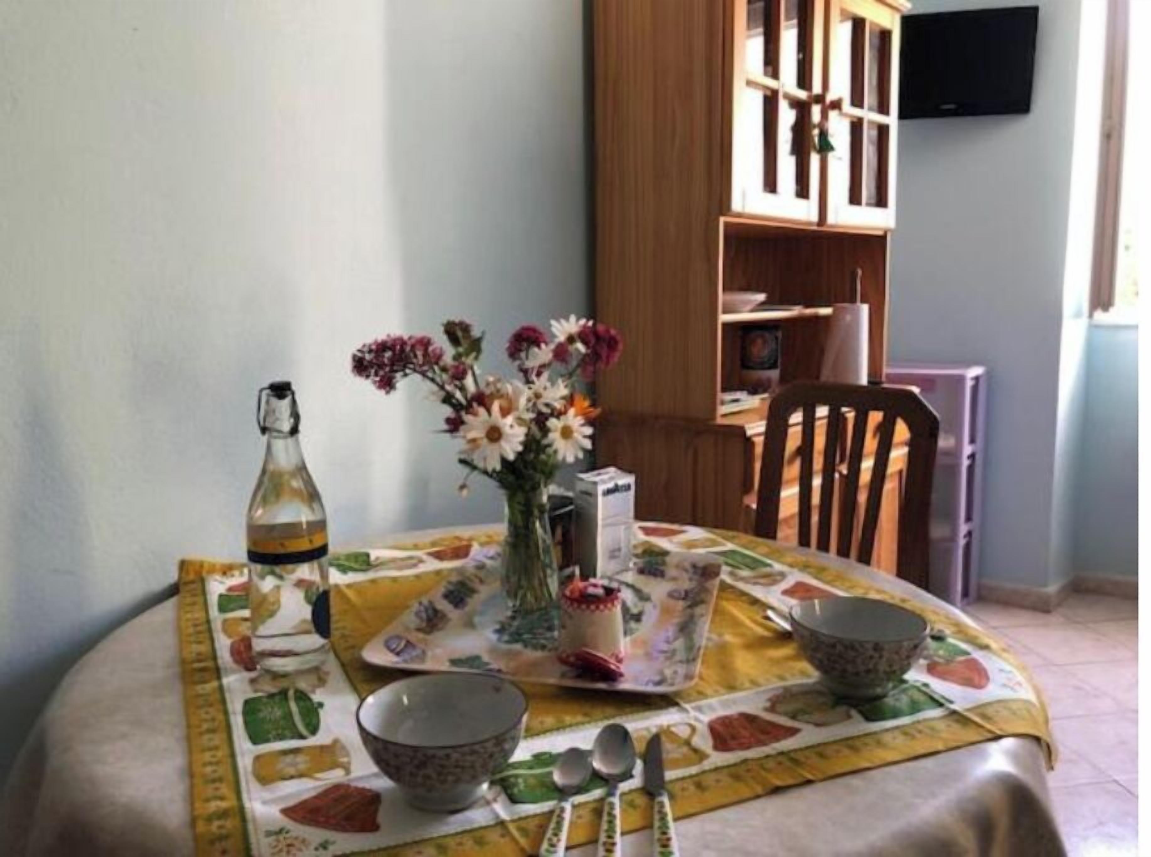A dining table set with a floral centerpiece, a bottle, and a tray with a cake.