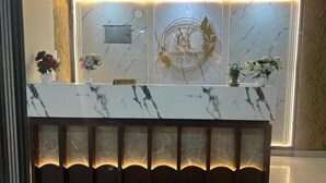 A reception desk with a marble top, a logo, and two flower arrangements. - HOTEL VIJAYA GRAND  (Patna)