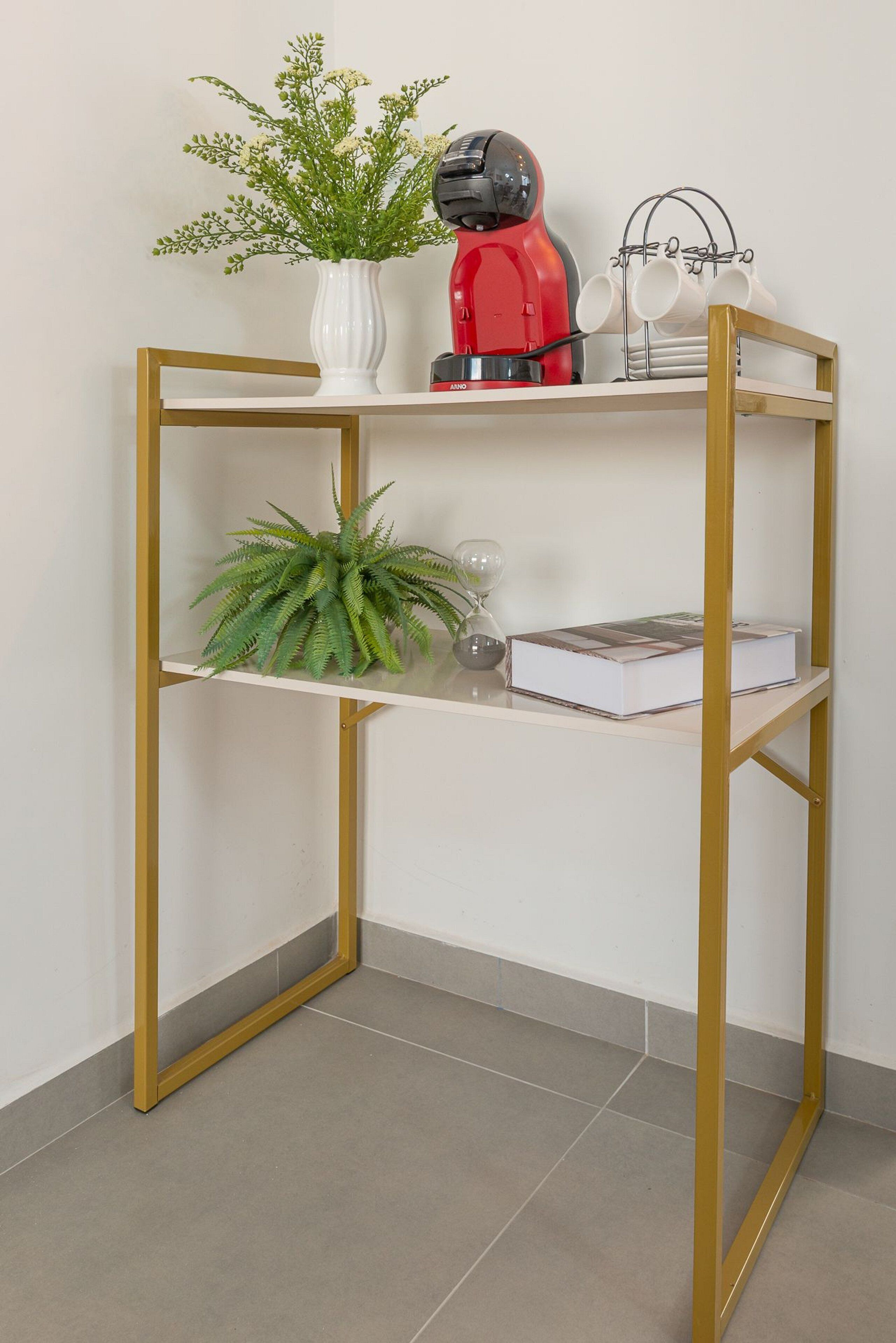A white and gold metal-framed shelf with a potted plant, a book, and a red kettle.