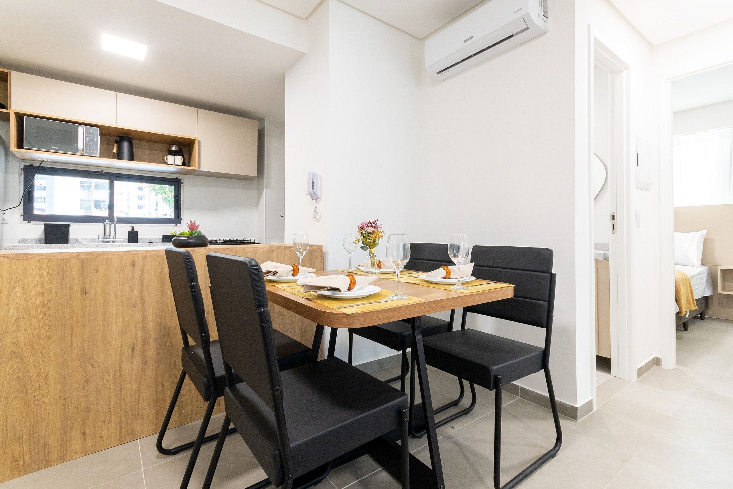 Una cocina moderna con una mesa de comedor para cuatro personas, un microondas y una cafetera.