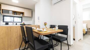 Una cocina moderna con una mesa de comedor para cuatro personas, un microondas y una cafetera.
