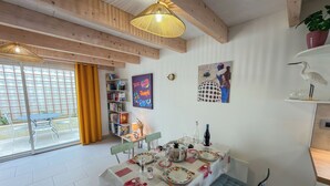En spiseplads med et bord dækket til fire personer, en bogreol og et billede på væggen.