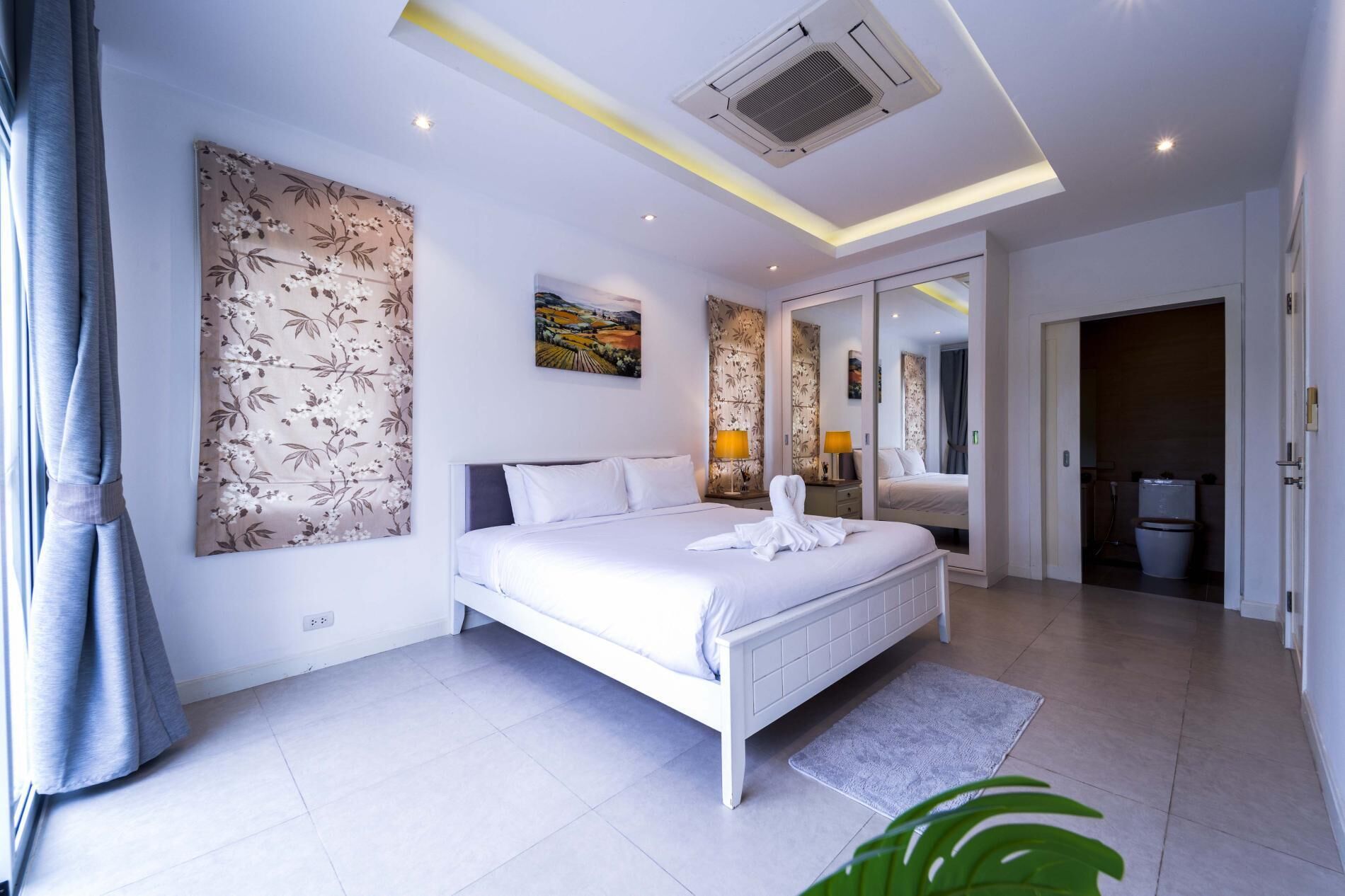 A modern bedroom with a large bed, a mirror, and a painting on the wall.