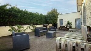Un patio al aire libre con mobiliario de mimbre, una parrilla y una terraza de madera.
