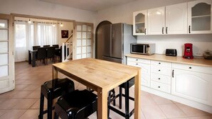 Una cocina moderna con armarios blancos, un refrigerador de acero inoxidable, una mesa de comedor de madera y sillas negras.
