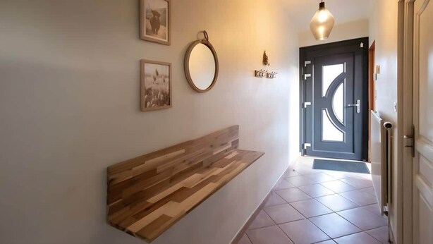 Un pasillo con un banco de madera, un espejo redondo y una puerta con diseño geométrico.