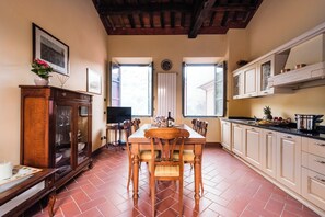 Een eethoek met een houten tafel en stoelen, een televisie en een kast met glazen deuren.