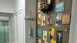 A hallway with a wall decorated with various posters and a ship model. - Beachfront apartment in Gonzaguinha (São Vicente)