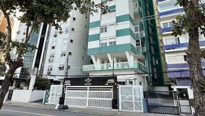 A multi-story building with a modern design, featuring a prominent green and white color scheme. - Beachfront apartment in Gonzaguinha (São Vicente)