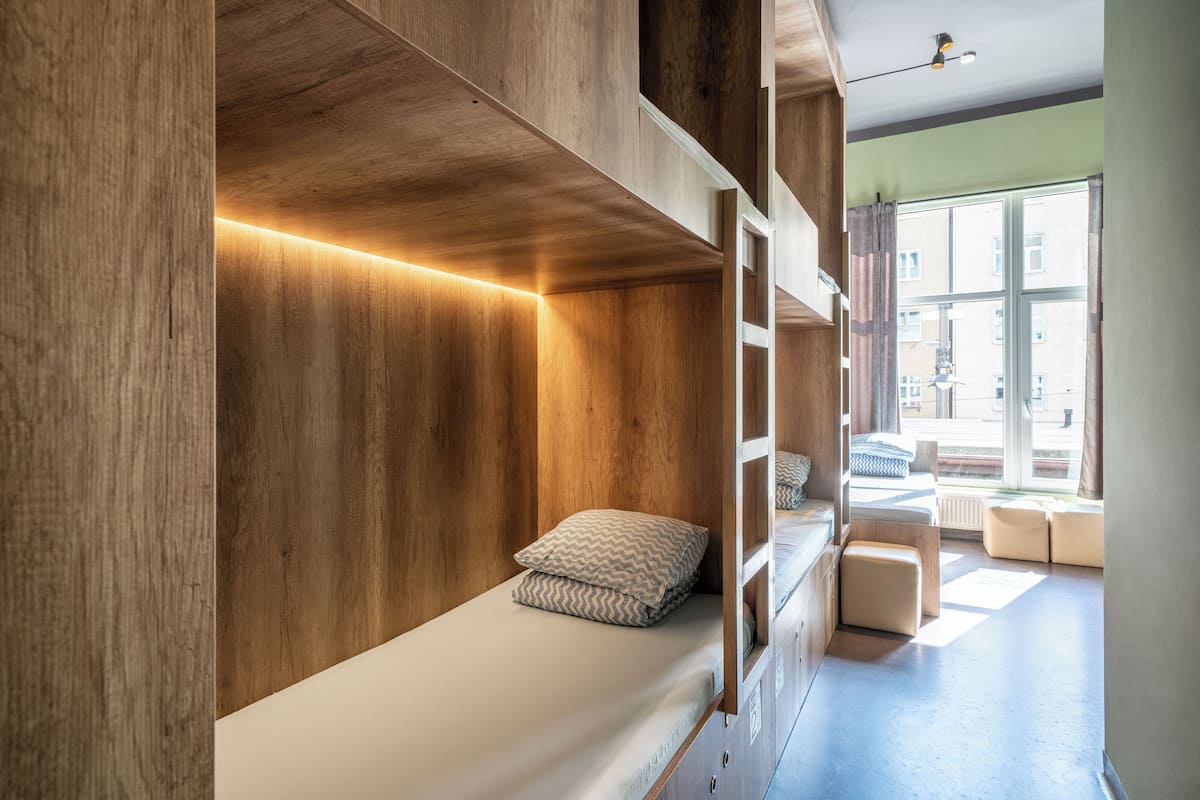 A bunk bed with wooden panels and a window with curtains.