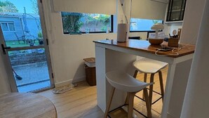 Eine kleine Küche mit Essbereich, einem Barhocker und einem Fenster mit Blick auf einen Garten.