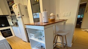Eine kompakte Küche mit einer zentralen Kochinsel, einer Waschmaschine und einem Hund unter der Arbeitsplatte.