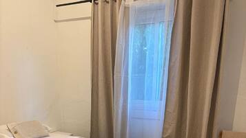 Ett sovrum med en säng, en stol och ett fönster med gardiner.