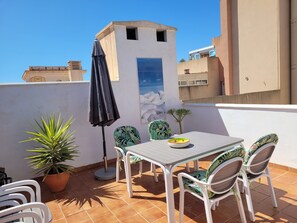 A terrace with a table and chairs, a potted plant, and a view of the sea. - Apartment in Nerja Near Sandy Beach (Nerja)