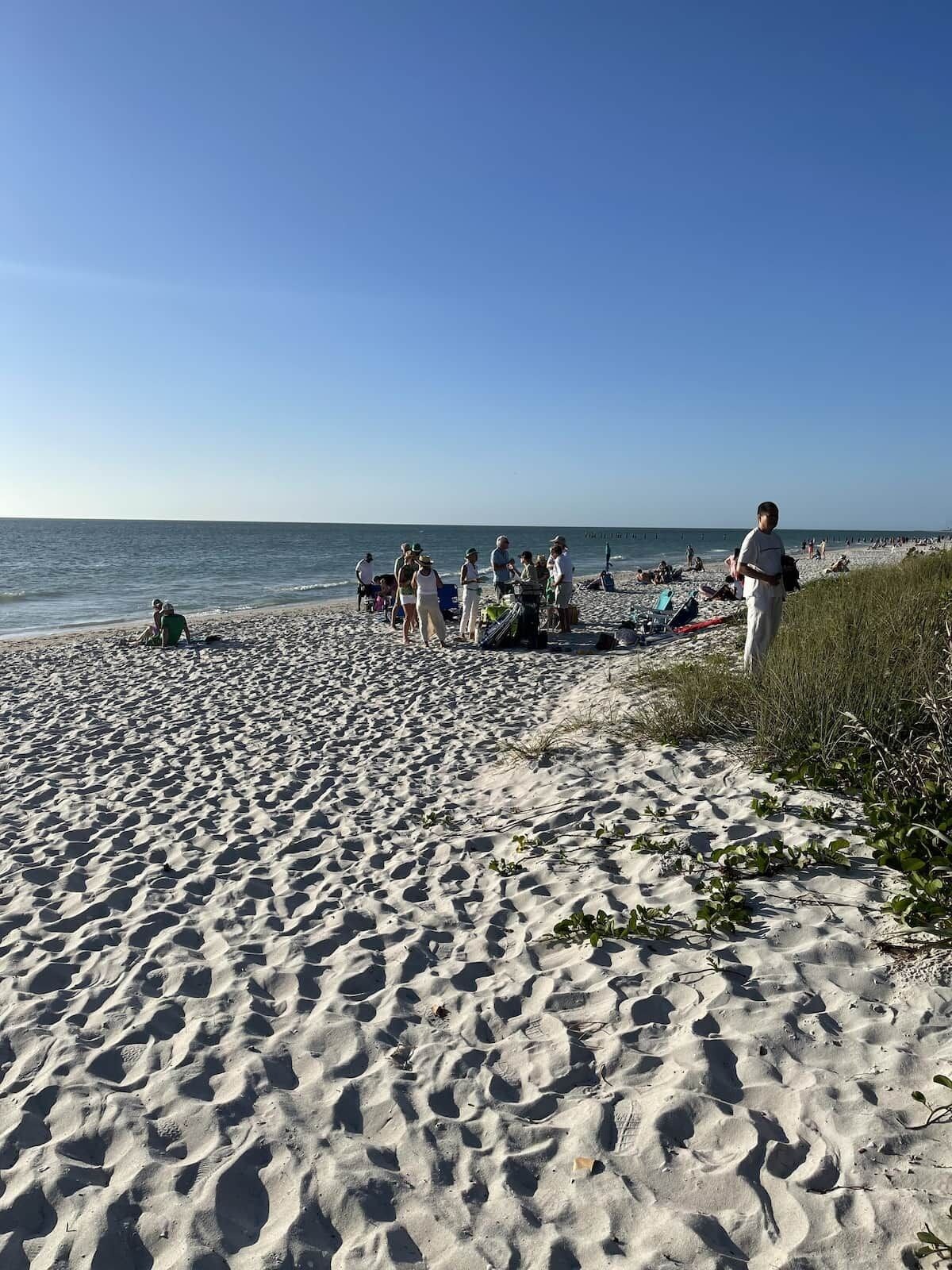 Une plage de sable où l’on voit des gens et des chaises de plage.