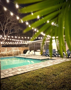 A backyard with a swimming pool, lounge chairs, and string lights. - Private Heated Pool-Near Naples Beaches-2BR/2BA (Naples)