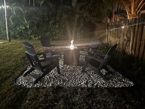 An outdoor seating area with a fire feature, surrounded by a wooden fence and tropical vegetation. - Private Heated Pool-Near Naples Beaches-2BR/2BA (Naples)