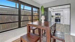 Eine moderne Küche mit weißen Schränken, Edelstahlgeräten und einem großen Fenster.