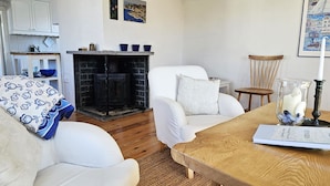 A cozy living room with a fireplace, white furniture, and a wooden coffee table. - Charming cottage by the sea in Stocken | SE09171 (Ellös)