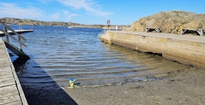 Un muelle se adentra en aguas tranquilas, con una costa rocosa al fondo.