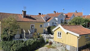 A row of yellow houses with red-tiled roofs, a wooden staircase, and a white picket fence. - Charming cottage by the sea in Stocken | SE09171 (Ellös)