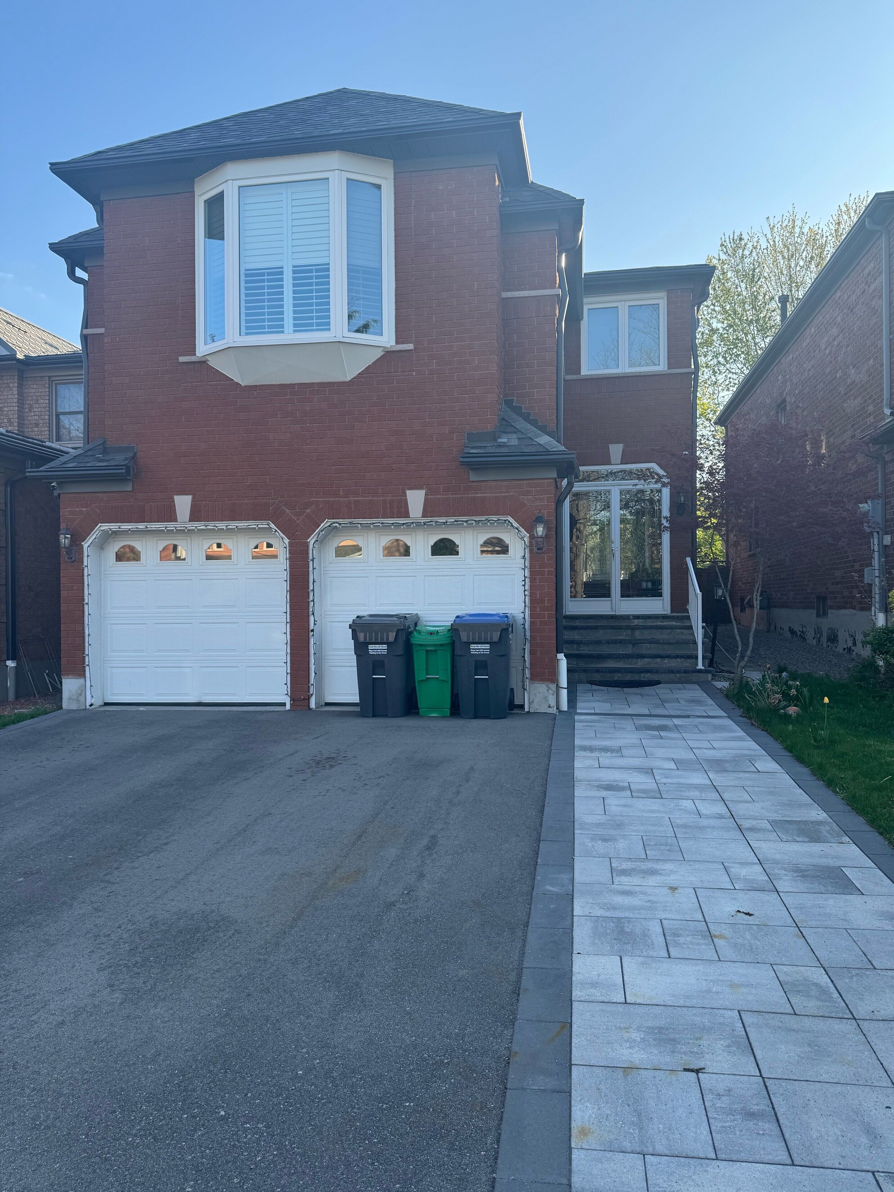 A two-story house with a garage, a driveway, and a sidewalk.