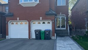 Ein zweistöckiges Haus mit Garage, Auffahrt und Bürgersteig.