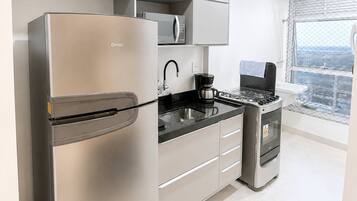 Cozinha moderna com eletrodomésticos de aço inoxidável, bancada preta e vista pela janela.