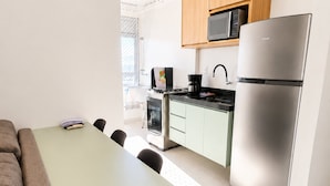 Eine moderne Küche mit Essbereich, ausgestattet mit einem Edelstahl-Kühlschrank, einer Mikrowelle und einer Kaffeemaschine.