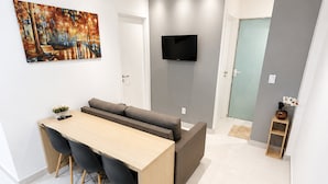 Ein zeitgemäßer Wohnraum mit Essbereich, einer Couch, einem Flachbildfernseher und einem Gemälde an der Wand.