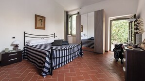 A bedroom with a bed, bedside table, lamp, and a window with a view of greenery. - Superior Apartment Borgo di Matraia (Matraia)