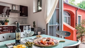 A modern kitchen with dark cabinets, a stainless steel range hood, and a window overlooking a red building. - Superior Apartment Borgo di Matraia (Matraia)