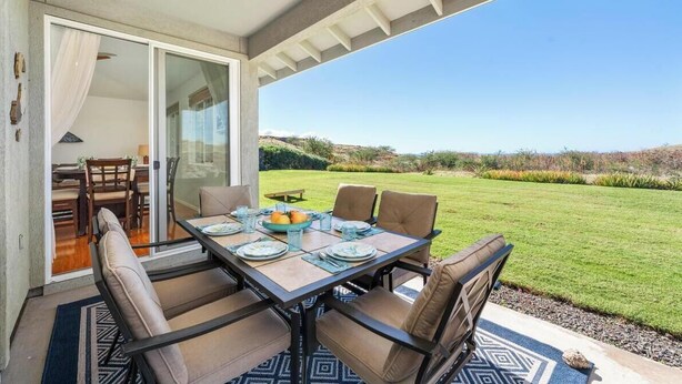 A dining area with a table set for six, surrounded by chairs, and a view of a grassy landscape. - Newly Remodeled Home in Waikoloa Village!  WeloWelo House (Waikoloa Village)