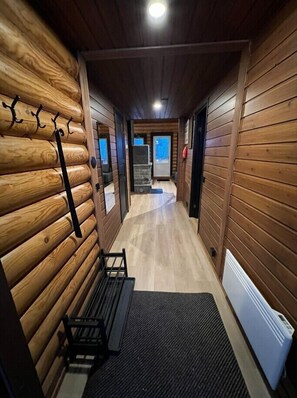 A wooden interior with a bench, a coat rack, and a door leading to another room.