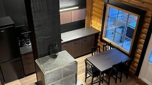 Uma cozinha compacta com fogão de pedra, armários de madeira e área de jantar com mesa e cadeiras.