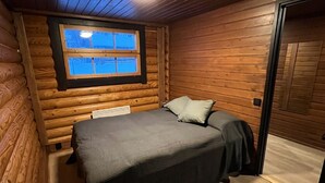A wooden cabin bedroom with a bed, a window, and a door. - Cottage Lomahimos 18 (Jämsä)