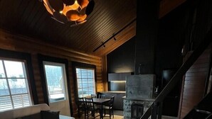 A cozy cabin interior with a fireplace, wooden walls, a dining area, and a staircase. - Cottage Lomahimos 18 (Jämsä)