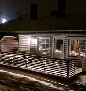 A log cabin with a covered porch, a fireplace, and a snow-covered ground. - Cottage Lomahimos 18 (Jämsä)