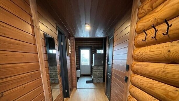 A narrow hallway with wooden walls and a wooden floor, leading to a door at the end. - Cottage Lomahimos 18 (Jämsä)