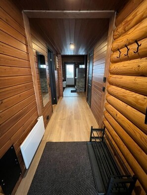 A narrow hallway with wooden walls and a wooden floor, leading to a door at the end. - Cottage Lomahimos 18 (Jämsä)