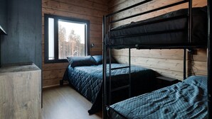 A room with wooden walls, a bunk bed, a desk, and a window with a view of trees.
