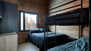 Huoneessa on puuseinät, kerrossänky, työpöytä ja ikkuna, josta avautuu näkymä puihin.