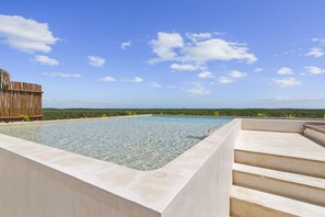 Une piscine aux eaux cristallines, avec une vue sur l’horizon et une clôture en bois en arrière-plan.