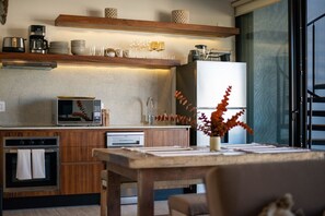 A modern kitchen with wooden cabinets, a microwave, a coffee maker, and a dining area with a table and chairs. - Sleeps 6 w Private Rooftop Pool & 2 Bikes (Tulum)