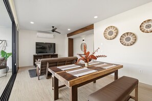 A dining area with a wooden table, benches, and a TV in the background. - Sleeps 6 w Private Rooftop Pool & 2 Bikes (Tulum)