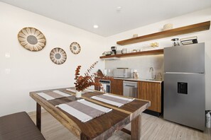 Une cuisine moderne avec une table à manger en bois, des appareils électroménagers en acier inoxydable et des œuvres d’art décoratives au mur.