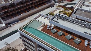 Une piscine sur le toit, dotée de chaises longues et d’une terrasse en bois.