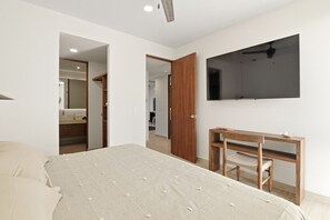 A bedroom with a bed, a wooden desk, a chair, a TV mounted on the wall, and a wardrobe. - Sleeps 6 w Private Rooftop Pool & 2 Bikes (Tulum)