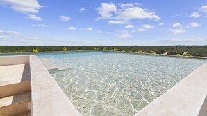 A clear swimming pool with steps leading into it, surrounded by a clear sky and distant greenery. - Ts'íibol: 3BR w Private Rooftop Deck & Pool (Tulum)